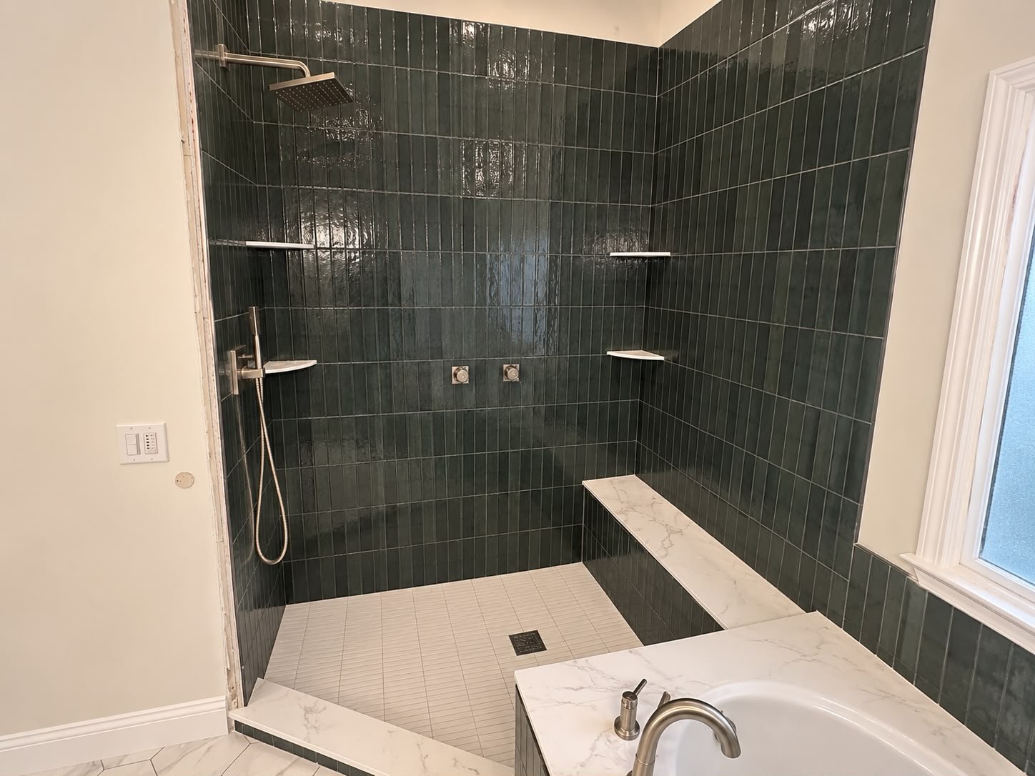 Completed walk-in shower with green tile, built-in bench, shelves and rainfall shower fixture